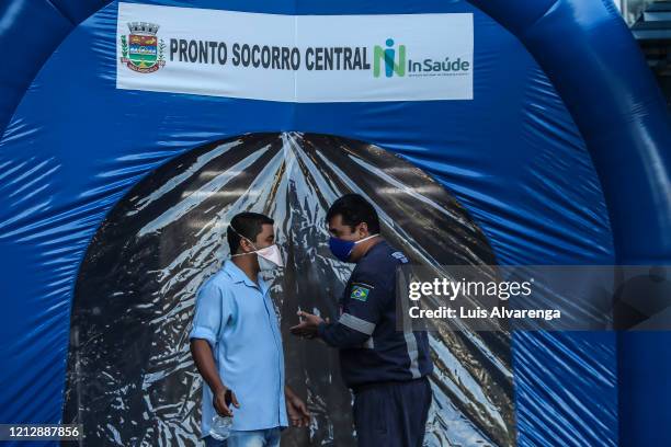 Health workers talk in front a disinfection tunnel at Dr. Armando Gomes de Sá Couto ER during the coronavirus pandemic on May 13, 2020 in São...