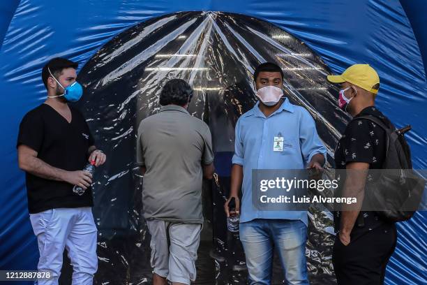 Hospital employee talks to people in front a disinfection tunnel at Dr. Armando Gomes de Sá Couto ER during the coronavirus pandemic on May 13, 2020...