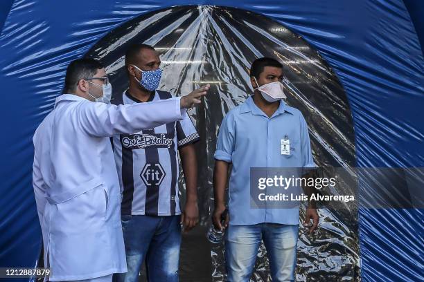 Health worker gives instructions in front of a disinfection tunnel at Dr. Armando Gomes de Sá Couto ER during the coronavirus pandemic on May 13,...