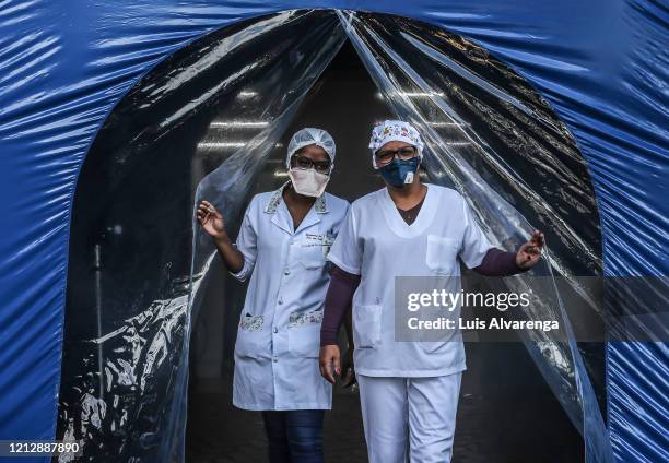 Health professionals wearing face masks stand in front of a disinfection tunnel at Dr. Armando Gomes de Sá Couto ER during the coronavirus pandemic...