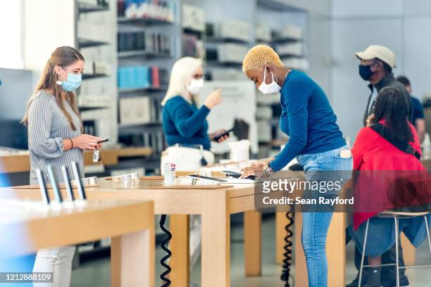 Employees at the Apple Store help customers on May 13, 2020 in Charleston, South Carolina. Customers had temperatures taken and were required to wear...