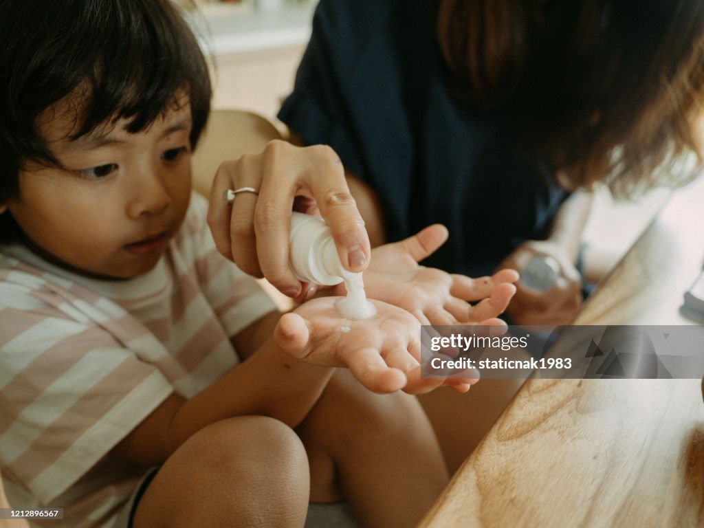 Mother cleaning her son`s hands with alcohol hand sanitizer protect her child from viruses