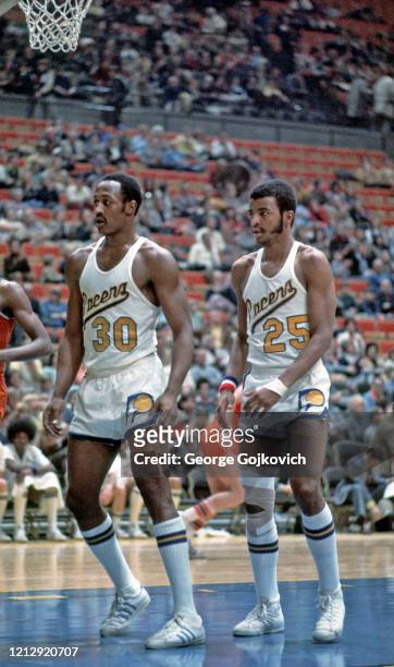 Forwards George McGinnis and Billy Knight of the Indiana Pacers look on from the court during an American Basketball Association game against the...