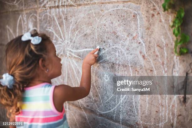 cheerful little girl having fun painting wall - chalk wall stock pictures, royalty-free photos & images