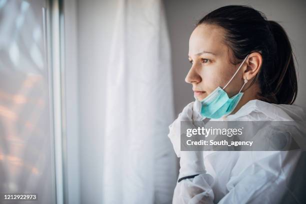 ongerust gemaakte vrouwelijke arts die door het het ziekenhuisvenster kijkt - allergy doctor stockfoto's en -beelden