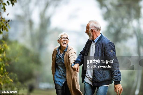 coppia senior giocosa che si diverte nel parco. - pensionamento foto e immagini stock