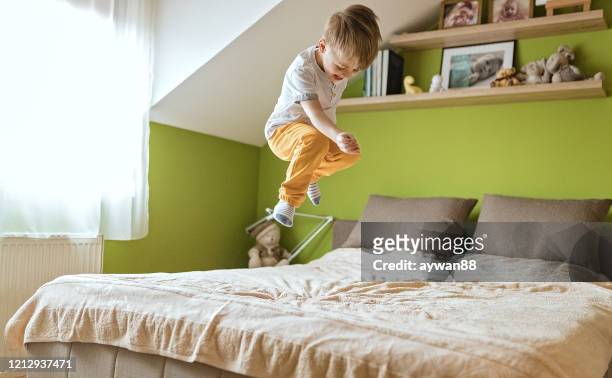 niño pequeño saltando en la cama - a boy jumping on a bed fotografías e imágenes de stock