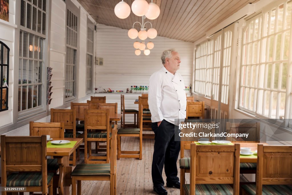 餐館老闆站在他空蕩蕩的餐廳裡。