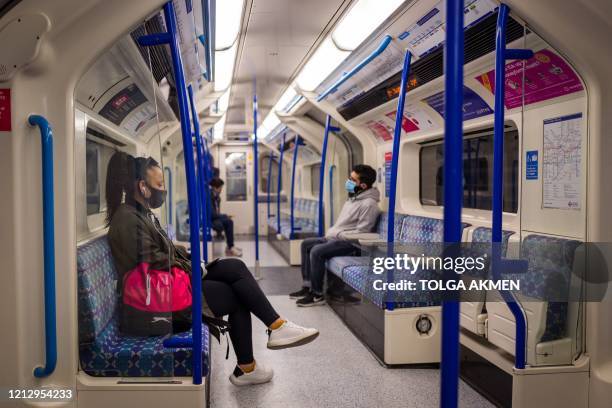 Passengers sit in a quiet London Underground tube train in London on May 14, 2020 after a partial loosening of the coronavirus lockdown guidelines. -...