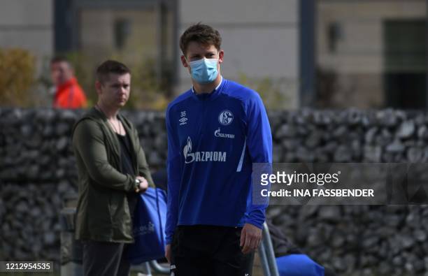 Schalke 04's German goalkeeper Alexander Nuebel walks with a face mask from the hotel, where the team stays in quarantine, to the club's training...