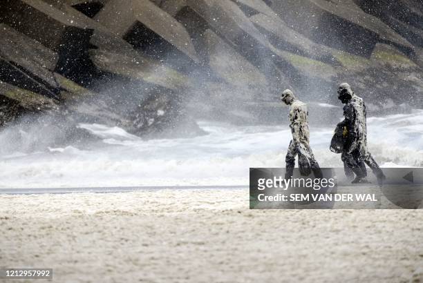 Military personnel walk beside beachside rocks at Scheveningen, The Netherlands, on May 14 as they search for the body of a surfer who was killed...