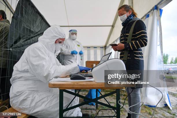 May 2020, Saxony-Anhalt, Weißenfels: A servant of the Burgenland district introduces herself to soldiers for a corona smear. In a test centre set up...