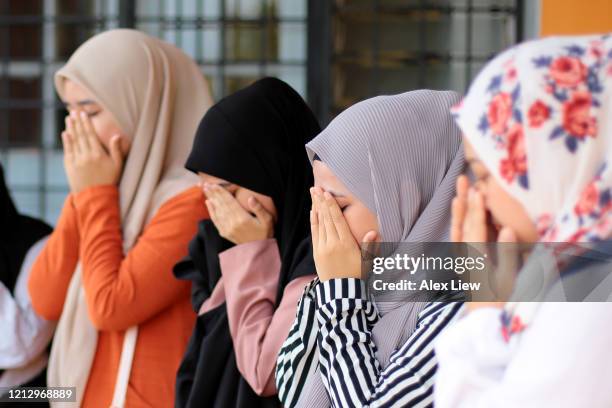 mujeres musulmanas modernas orando - hiyab fotografías e imágenes de stock