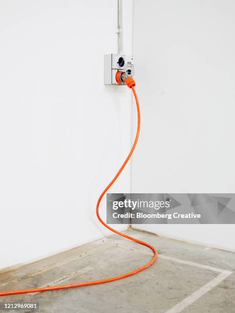 charging plug and orange power cable - charging cable stock pictures, royalty-free photos & images