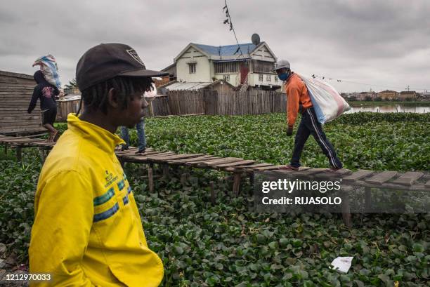 Residents of the Anjezika neighborhood help volunteers from the association Le Caméléon by transporting food parcels and clothing that will be...