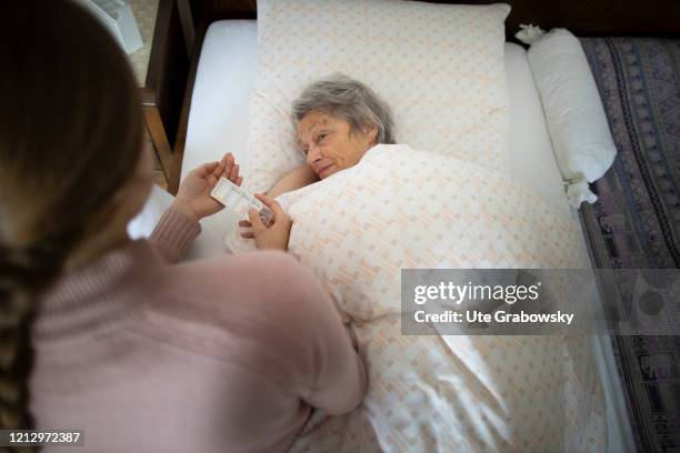 In this photo illustration a relative of the old woman hands out pills on May 12, 2020 in Radevormwald, Germany.