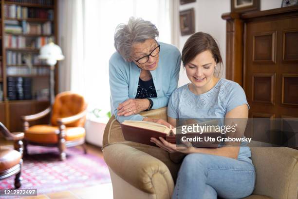 In this photo illustrationan old woman and a young woman looking into a photo book on May 12, 2020 in Radevormwald, Germany.
