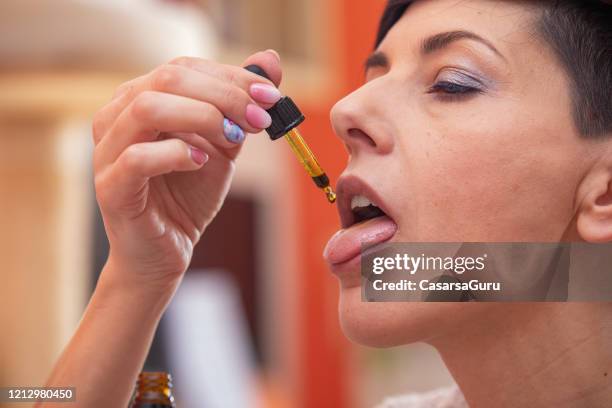donna adulta che usa olio di cannabis - foto di repertorio - human tongue foto e immagini stock