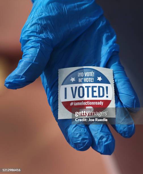 Voter holds an, 'I Voted!', sticker after wearing a glove as she cast her ballot during the Florida presidential primary as the coronavirus pandemic...