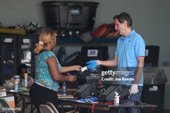 George Hanley A poll worker checks in George Hanley, who is wearing protective ...