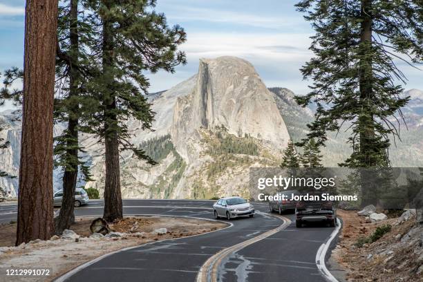 cars driving down a windy road in yosemite while on a road trip through the park. - mariposa county photos et images de collection