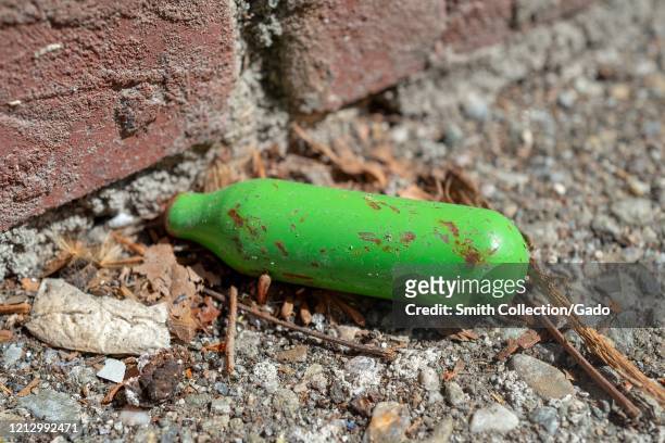 Close-up of miniature cylinder of nitrous oxide, a drug of abuse referred to as Whip Its, Whipits or Whippets, discarded in a gutter in Walnut Creek,...