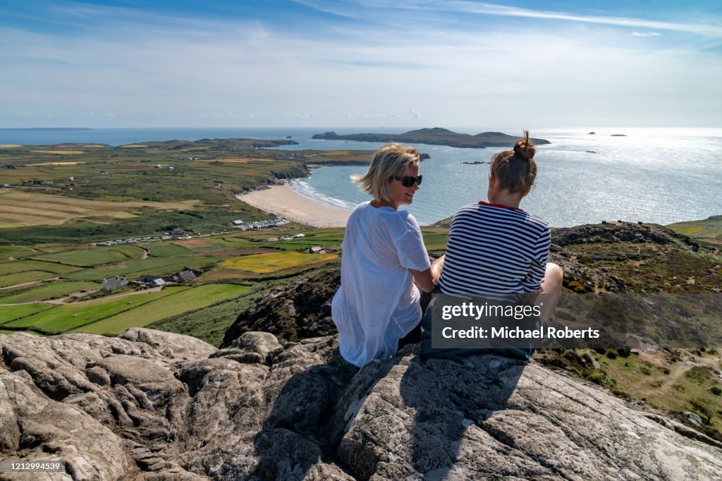 Rear view of mother and daughter chatting on a mountain top (Carn Llidi) overlooking Whitesands bay, Pembrokeshire