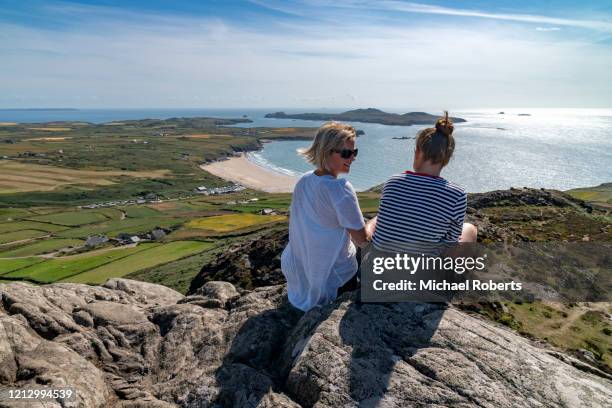 rear view of mother and daughter chatting on a mountain top (carn llidi) overlooking whitesands bay, pembrokeshire - pembrokeshire bildbanksfoton och bilder