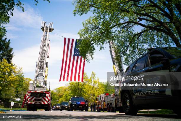 Huge American flag hangs over the procession during the funeral of Glen Ridge Police Officer Charles Roberts after he passed away from the...