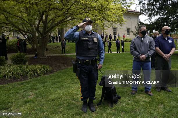 Montclair University officer salutes as pallbearers carry the casket of Glen Ridge Police Officer Charles Rob Roberts who died of coronavirus, weeks...