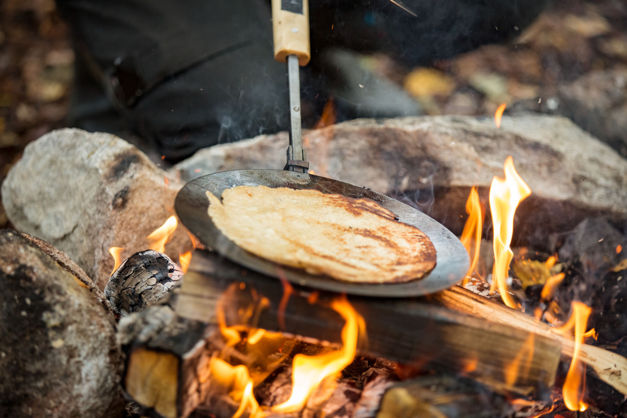 Man and woman making pancakes on campfire Man and woman making pancakes on campfire