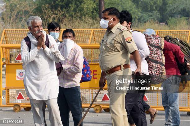 Migrants walking towards Uttar Pradesh are stopped by a police personnel at the Ghazipur Delhi-UP border on May 14, 2020 in New Delhi, India.
