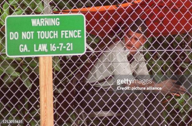 Ein Sicherheitsbeamter sitzt auf dem Gelände des Olympischen Dorfes in Atlanta am 14.7.1996 hinter dem Zaun, der das Dorf hermetisch abriegelt. Ein...