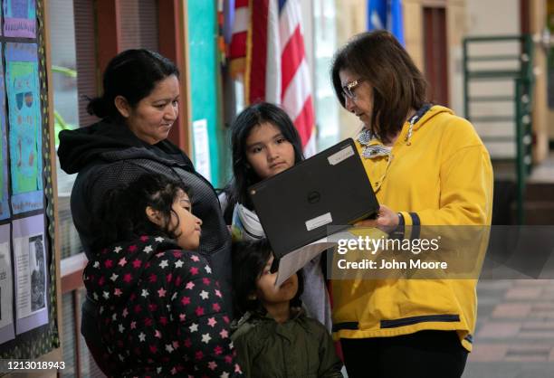 Bilingual teacher Maria Sanislo explains a Google Chromebook to a family at KT Murphy Elementary School on March 17, 2020 in Stamford, Connecticut....