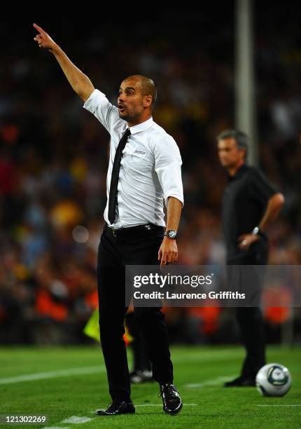 Josep Guardiola of Barcelona instructs his players in front of Jose Mourinho of Real Madrid during the Super Cup second leg match between Barcelona...