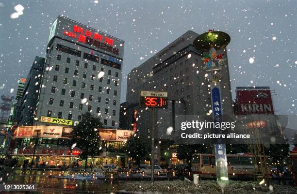 Eine Leuchtschrift neben einer riesigen Olympiafackel indiziert am auf dem Bahnhofsvorplatz von Nagano in Japan bei starkem Schneefall, daß es noch...