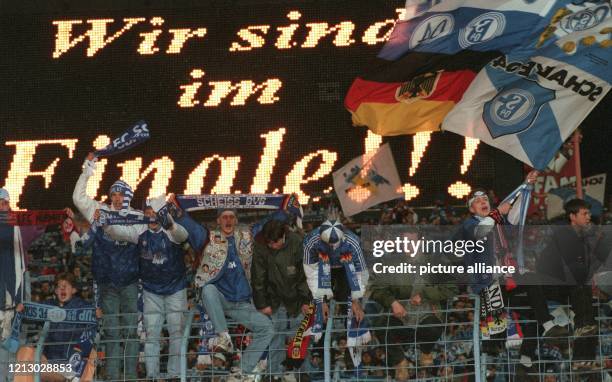 Vor der Anzeigentafel mit der Leuchtschrift "Wir sind im Finale" bejubeln am 22.4.1997 im Gelsenkirchener Parkstadion Schalkes Fans auf den Traversen...