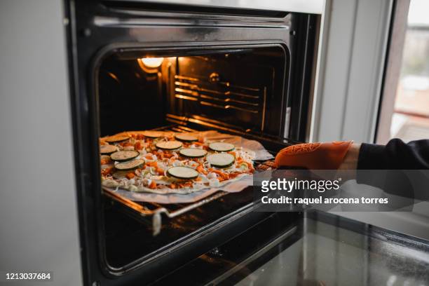 man putting a homemade pizza into the oven - making pizza stock pictures, royalty-free photos & images
