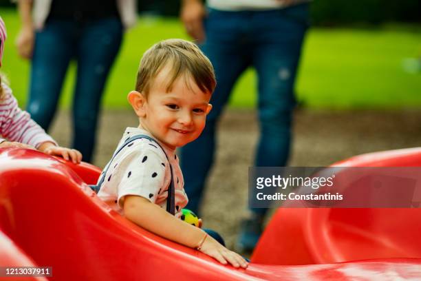 little boy is having fun at playground.parents in the background. - amber alert stock pictures, royalty-free photos & images