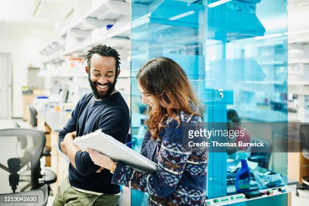 smiling scientists in discussion while filling out paperwork in research lab - innovation 協力する ストックフォトと画像