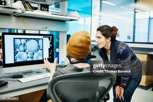 female scientists discussing microscope image on computer in research lab - biotechnology lab stock-fotos und bilder