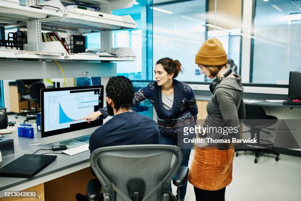 scientists examining data on computer while working in research lab - scrutiny foto e immagini stock