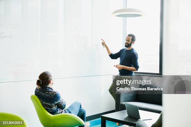 business colleagues discussing project data on whiteboard in conference room - guess jeans stock pictures, royalty-free photos & images
