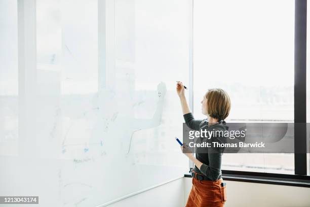 female scientists working on project data on whiteboard in research lab - woman whiteboard stock pictures, royalty-free photos & images