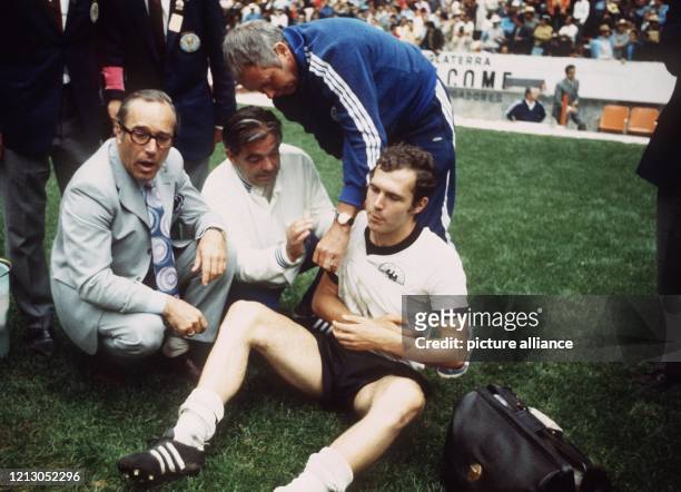 Der deutsche Abwehrspieler Franz Beckenbauer hat sich in der 2. Halbzeit an der Schulter verletzt und wird auf dem Rasen sitzend von Hermann Joch vom...