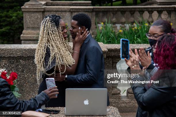 Jameila Rambana 2nd from L, and Andre Rambana 3rd from L, hold one another after sealing their marriage with a kiss while surrounded by Andre's...