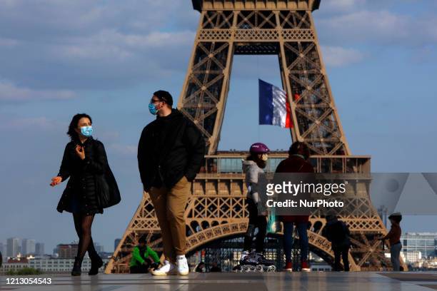 People walk a front the Eiffel Tower in Paris on May 14 on the fourth day of a partial lifting of a near two month lockdown imposed in France to stop...