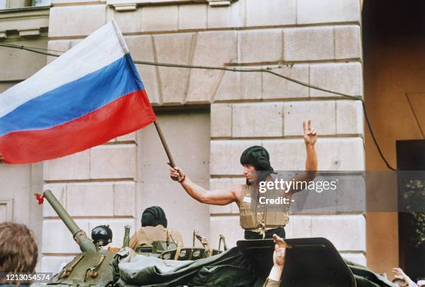 Soldier waves 21 August 1991 a Russian flag from the top of his tank as armoured units leave their positions in Moscow following the collapse of the...