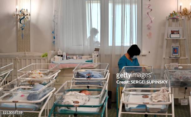 Nurse cares for newborn babies at Kiev's Venice hotel on May 15, 2020. - More than 100 babies born to surrogate mothers have been stranded in Ukraine...