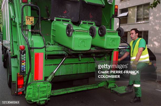 Un employé de la ville de Paris vide des poubelles destinées au verre dans la benne du camion, en août 2002 à Paris.